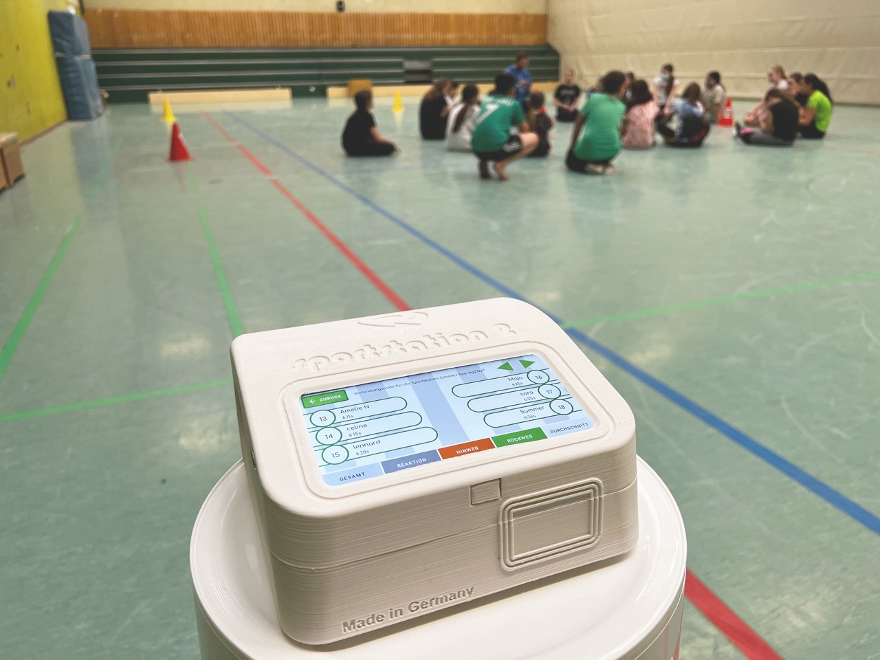 sportstation2 in einer Schulhalle mit Kindern im Hintergrund